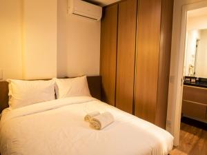 a bed with a pair of towels on top of it at Campos Sales by Xtay - Studios completos na região judiciária de Juvevê in Curitiba