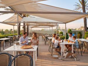 a group of people sitting at tables on a patio at Camping Castelló Mar in Empuriabrava