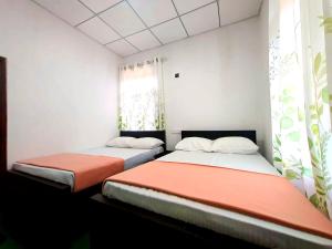 two beds in a room with white walls and a window at Haputale Hills Holiday Home in Haputale