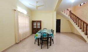 a dining room with a table and chairs and a staircase at Villa 9 degrees north in Sultan Bathery