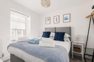 a bedroom with a bed with blue and white pillows at Seas the Day - Moments from Hamworthy Beach and Park in Poole