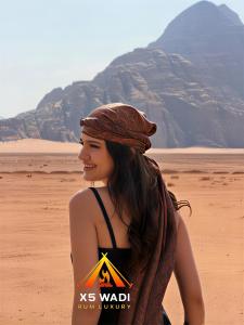 a woman wearing a hat standing in the desert at X5 wadi Rum Luxury in Wadi Rum