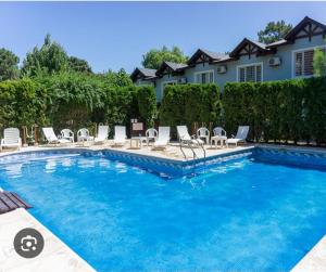 a swimming pool with chairs and a house at VALERIA 4 Ambientes in Valeria del Mar