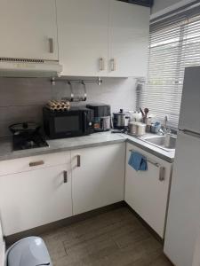 a kitchen with white cabinets and a sink and a microwave at Le belgique ,1 minute plage in Vallauris