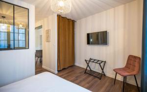 a bedroom with a bed and a chair and a tv at Le Parvis in Rodez