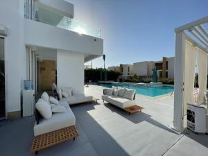 a patio with white couches and a swimming pool at Seashell 2nd row sea Villa in El Alamein