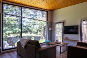 a living room with a large window and a tv at Ventania Golf Resort in Sierra de la Ventana