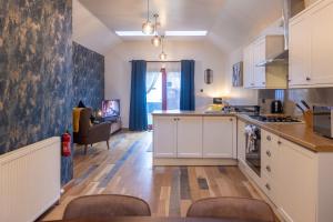 a kitchen with white cabinets and a table and chairs at Luss Cottages at Glenview in Luss