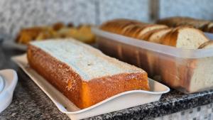 two loafs of bread on a counter with other bread at Hotel Pousada Executiva Itabuna in Itabuna