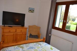 a bedroom with a television on a dresser with a chair at L'ESCALE SINAGOTE Gîte in Séné
