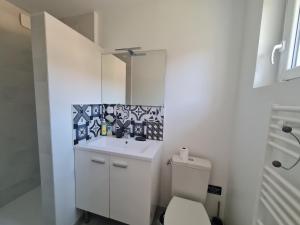 a white bathroom with a sink and a toilet at La Petite Sommière in Besançon
