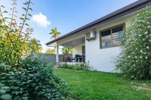 a white house with a window and a yard at Moorea bungalow cosy proche plage de Temae in Moorea +26 photos