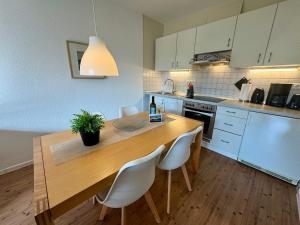 a kitchen with a wooden table and white chairs at Altes Wasserwerk App 10 in Wustrow +6 photos