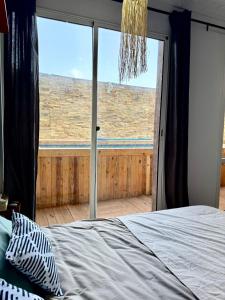 a bedroom with a bed and a large window at Zeri Surf Taghazout Hiltop in Taghazout