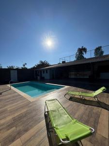 a swimming pool with two lawn chairs on a deck at Chácara Conquistando II in Jarinu