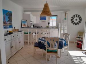 a kitchen with a table and some chairs and a table and a table andktop at L'écrin des Ormeaux - sur l'île - 300 m de la plage in Barbâtre +2 photos