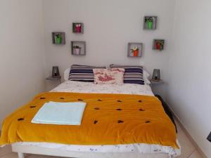 a bedroom with a large bed with a yellow blanket at L'écrin des Ormeaux - sur l'île - 300 m de la plage in Barbâtre