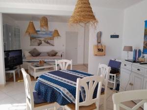 a room with a table and chairs and a kitchen at L'écrin des Ormeaux - sur l'île - 300 m de la plage in Barbâtre