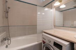 a bathroom with a tub and a washing machine at Madach City Studio in Budapest