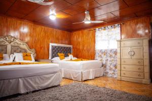 a bedroom with two beds and a dresser at Master Universel Hotel Bar Restaurant in Cap-Haïtien