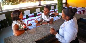 a man and two women sitting at a bar with wine glasses at Master Universel Hotel Bar Restaurant in Cap-Haïtien