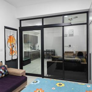 a living room with a couch and a living room with glass doors at Eduscentral Stanford, Setia Alam in Shah Alam