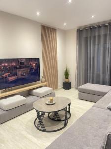 a living room with a large tv and a table at Pearl Luxury Suites in Paralia Dionysiou +55 photos
