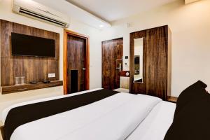 a bedroom with a white bed and a flat screen tv at Townhouse OAK The Hotel Square Villa in Ghaziabad +27 photos