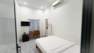 a white room with a bed and a desk at Mini hotel Lạc Hồng in Hue