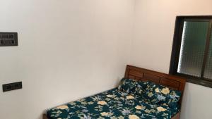 a bedroom with a bed with a floral sheets and a window at Rmeshwar homestay in Malvan