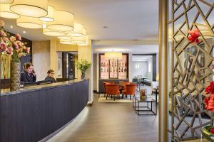 a lobby of a hotel with a woman sitting at a counter at Hotel Aragon in Bruges