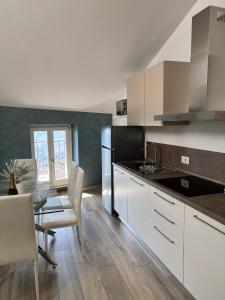 a kitchen with white cabinets and a table with chairs at Appartamenti Lilla in Tremosine Sul Garda