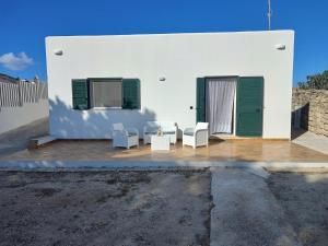 a white building with green doors and white chairs at villa ingrassia in Favignana