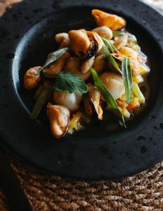 a black bowl of food with mushrooms and greens at Nomad Greenland Camp Saqqaq in Saqqaq