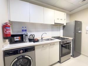 a kitchen with a washing machine and a sink at Charming Hideaway Studio with Cozy Views in Ras al Khaimah