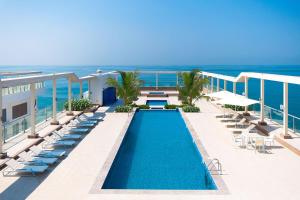 a swimming pool on a balcony with chairs and the ocean at Charming Hideaway Studio with Cozy Views in Ras al Khaimah