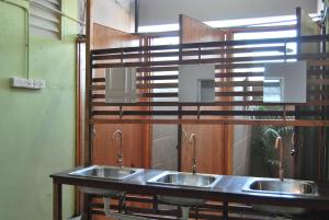 eine Reihe von drei Waschbecken in einer öffentlichen Toilette in der Unterkunft Borneo Sweet Guesthouse in Kuching
