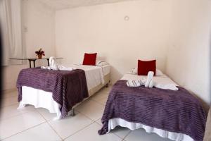 two beds in a white room with red pillows at Pousada Marajoara- Hotel Fazenda-Turismo de Aventura in Soure