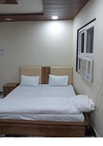 a bedroom with a bed with white sheets and a window at Hotel Baghdad Palace in Jāmb
