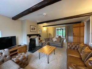 a living room with couches and a television and a table at Cottage No1 Four Bed Lakeland Retreat and Hot Tub in Elterwater