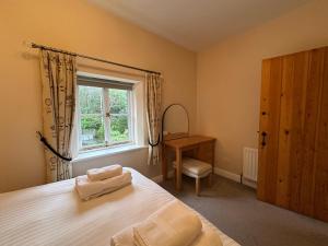 a bedroom with a bed and a window and a chair at Cottage No1 Four Bed Lakeland Retreat and Hot Tub in Elterwater