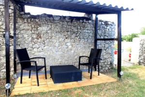 a patio with three chairs and a table and a stone wall at Au clocher in Saint-Seurin-de-Cadourne