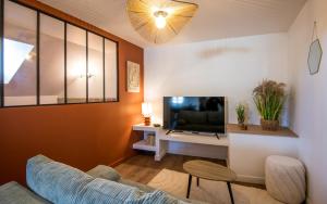 a living room with a couch and a tv at La Nef - Climatisation, Parking & Wifi à 150m de la Cathédrale in Rodez