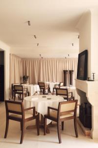 a dining room with white tables and chairs and a fireplace at Les Sources de Vougeot in Vougeot