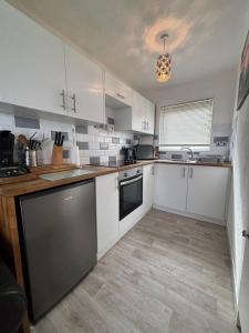 a kitchen with white cabinets and a counter top at 121 Sunbeach - Two bed Chalet at Scratby - Sleeps 5, pet friendly - plus WiFi, bed linen and towels included - FREE swimming passes and Entertainment - Only 300m from the beach in Scratby