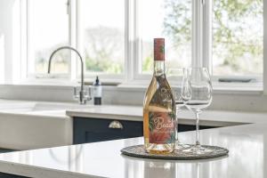 a bottle of wine sitting on a counter with two wine glasses at Cedar Barn in Chichester