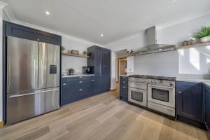 a kitchen with blue cabinets and stainless steel appliances at Cedar Barn in Chichester