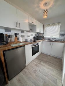a kitchen with white cabinets and a counter top at 121 Sunbeach - Two bed Chalet at Scratby - Sleeps 5, pet friendly - plus WiFi, bed linen and towels included - FREE swimming passes and Entertainment - Only 300m from the beach in Scratby +20 photos