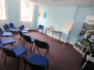 a classroom with blue chairs and a table and a whiteboard at YHA Alnwick - Partner in Alnwick