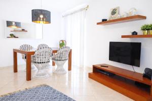 a living room with a tv and a table and chairs at Avenue Apartment - Family-friendly T2 - Estacionamento Privado in Quarteira
